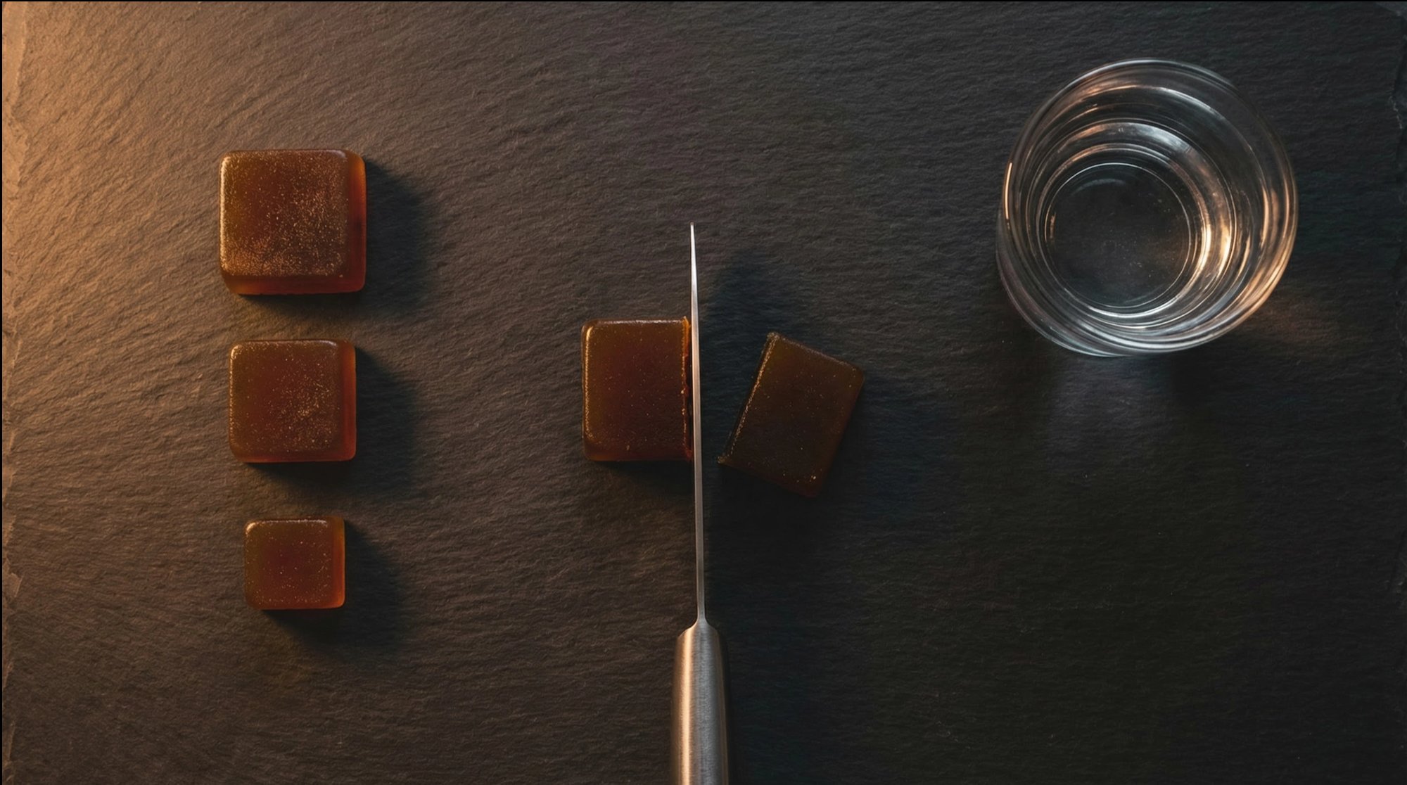Gummy cut in half with knife on dark slate showing precise dosing
